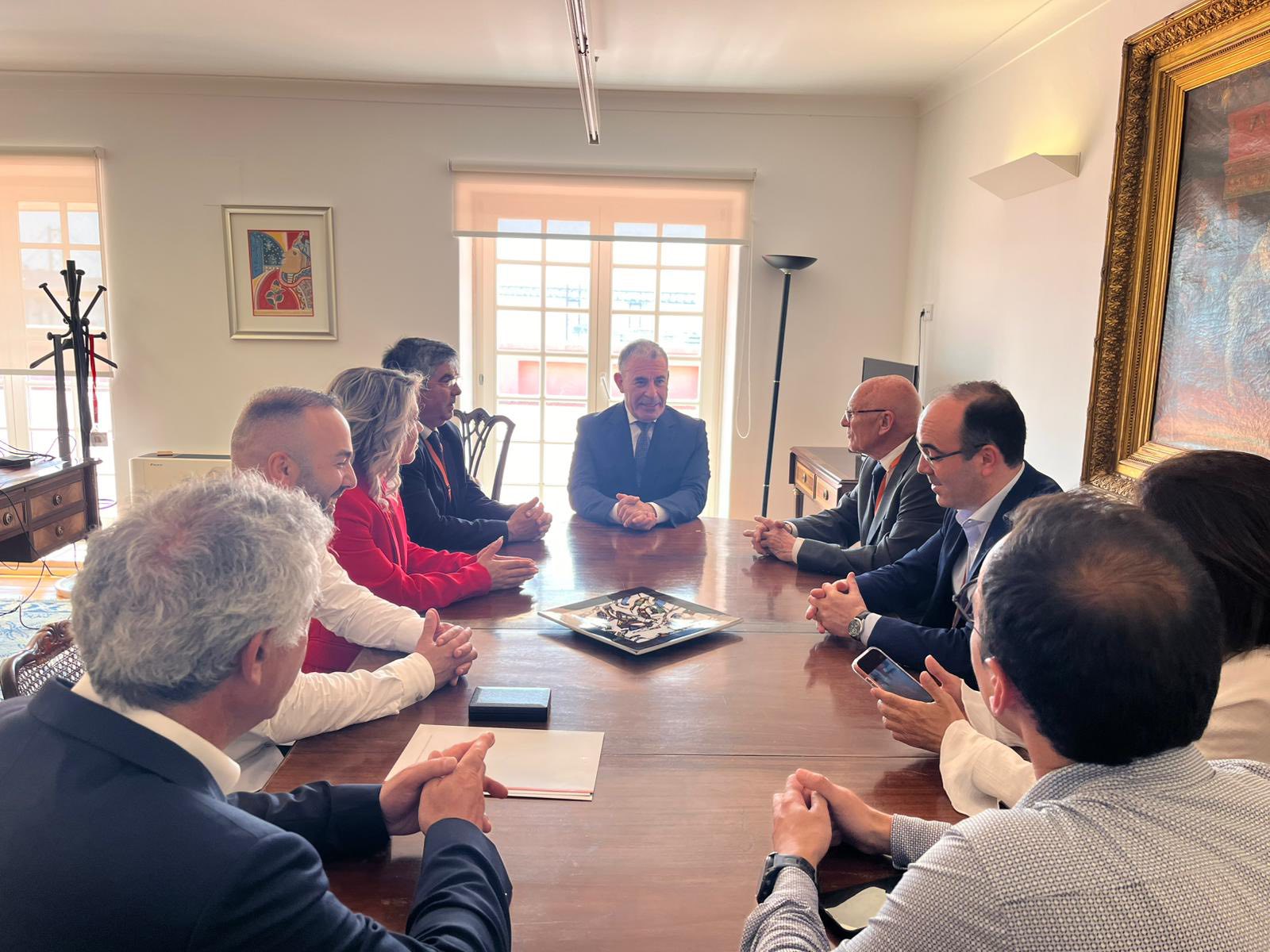 Grupo de pessoas sentadas à volta de uma mesa de reuniões, num ambiente formal, durante a entrega de uma distinção oficial.