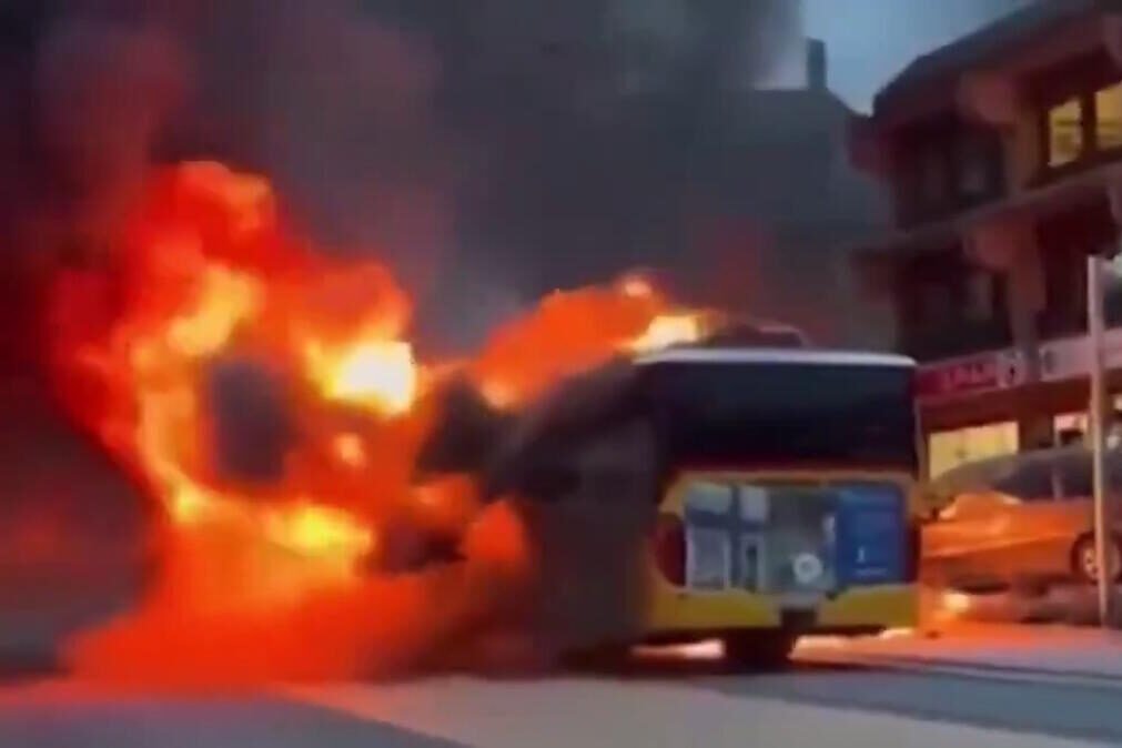 Autocarro de transporte público envolto em chamas intensas numa rua urbana, ilustrando o incêndio descrito no artigo.